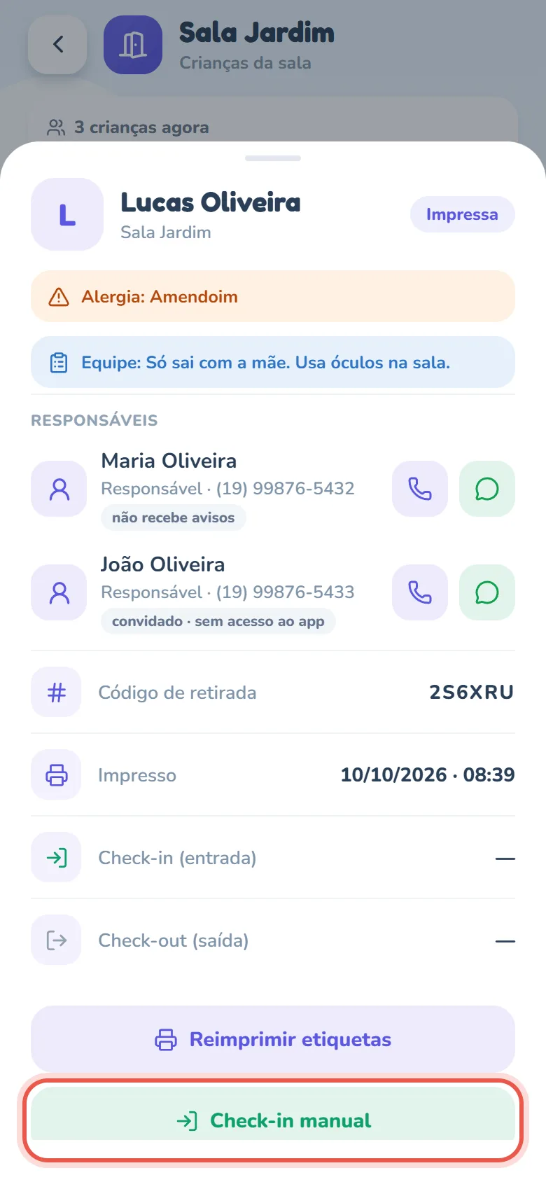 Ficha de Lucas Oliveira, da Sala Jardim, aberta sobre a lista: o selo Impressa, a faixa laranja Alergia: Amendoim, a faixa azul Equipe: Só sai com a mãe. Usa óculos na sala., o card Responsáveis com Maria Oliveira (selo não recebe avisos) e João Oliveira (selo convidado · sem acesso ao app) — cada um com o telefone e os botões de ligar e de WhatsApp —, as linhas Código de retirada, Impresso, Check-in (entrada) e Check-out (saída), ainda sem horário nas duas últimas, e, embaixo, os botões Reimprimir etiquetas e Check-in manual, este em destaque; a ficha continua rolando até Cancelar etiqueta (desistência) e Fechar.